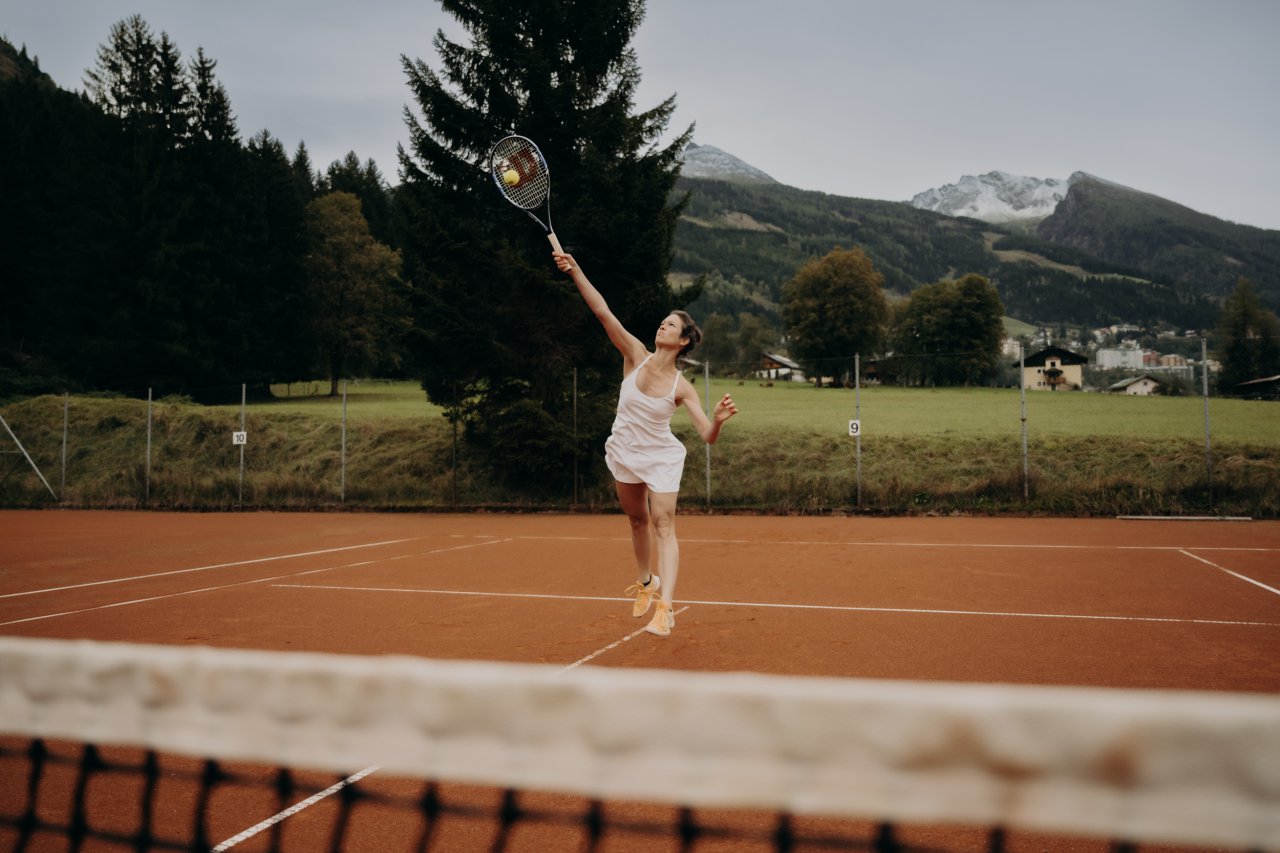 Tennisspielerin beim Aufschlag vor der Gasteiner Bergkulisse