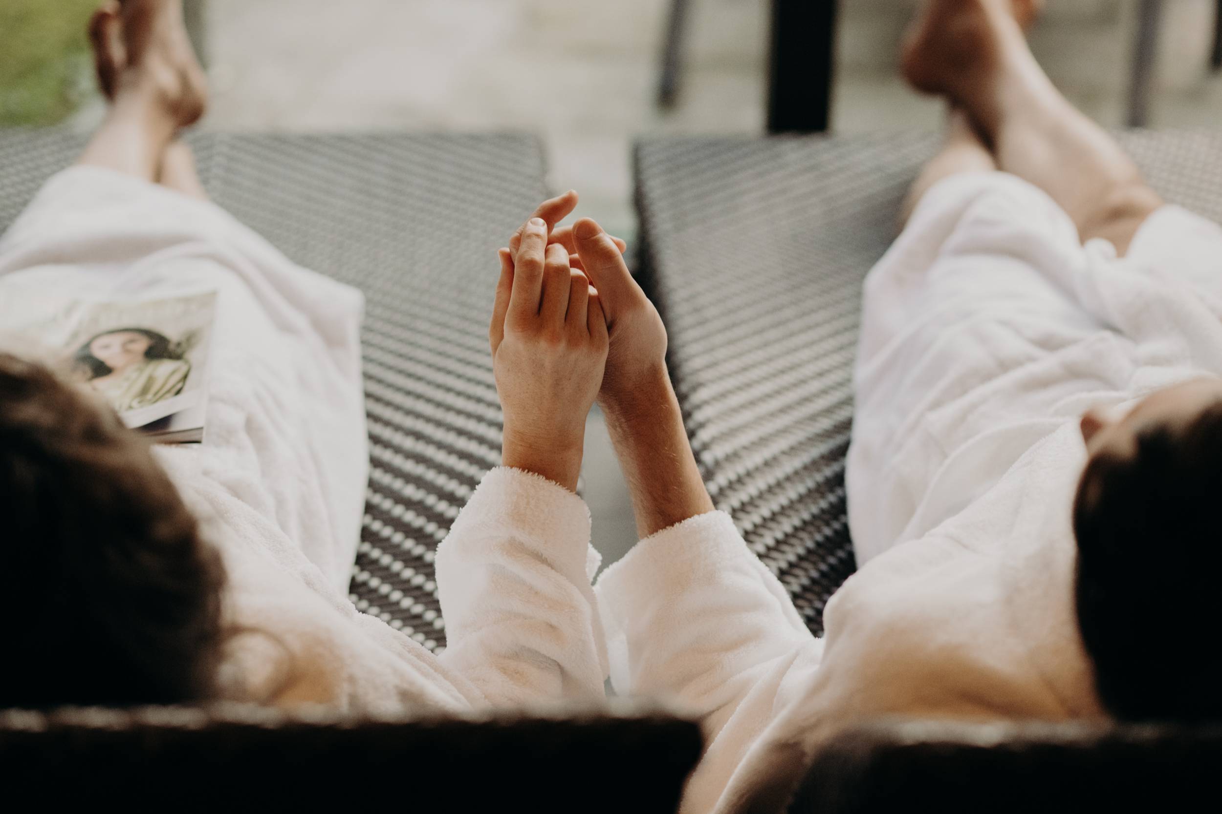 Paar hält Hände und liegt im Bademantel im Wellnessbereich