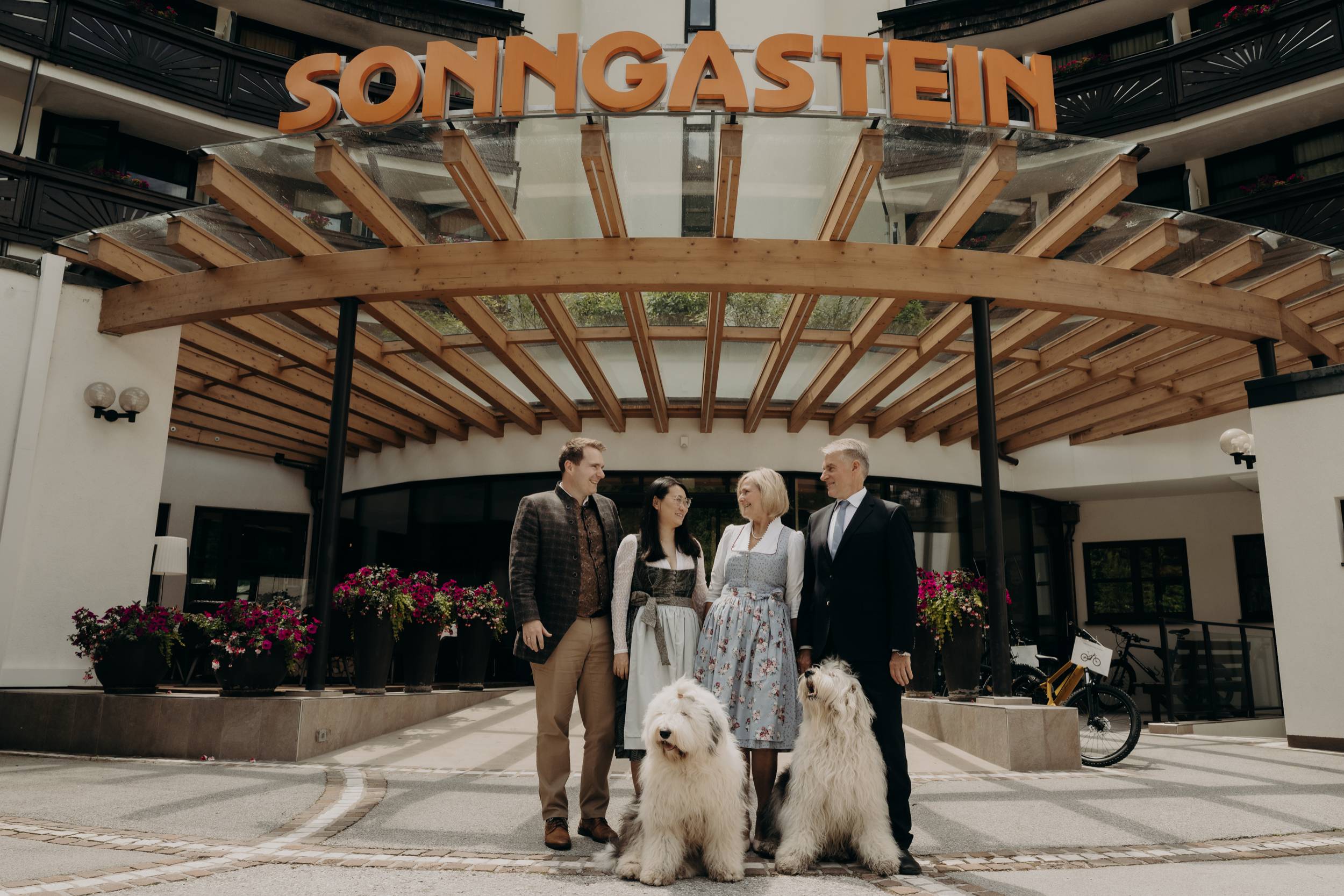 Family in front of Hotel Sonngastein in Bad Gastein with two dogs at the hotel entrance.