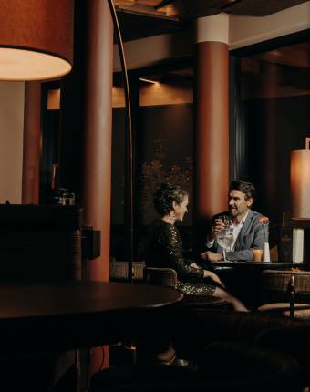 Mann und Frau sitzen in der Hotelbar, genießen Cocktails und unterhalten sich