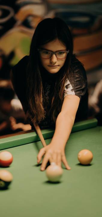 Mädchen konzentriert beim Billard spielen