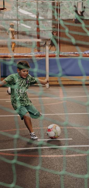 Junge beim Fussball spielen schießt auf das Tor