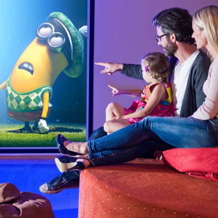 Vater, Mutter und Tochter schauen einen Film im Hotel-Kino