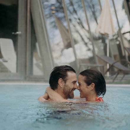 Ein Paar schaut sich verliebt in die Augen und umarmt sich im Hotelpool