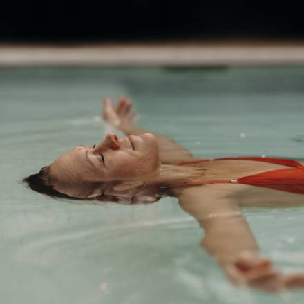 Eine Frau lässt sich im Wasser des Hotelpools treiben