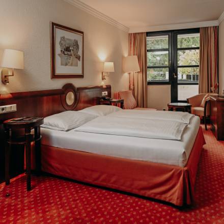 Geräumiges Hotelzimmer mit komfortablem Doppelbett, Sitzecke und großem Fenster – stilvolle Wohlfühlatmosphäre für erholsame Aufenthalte.