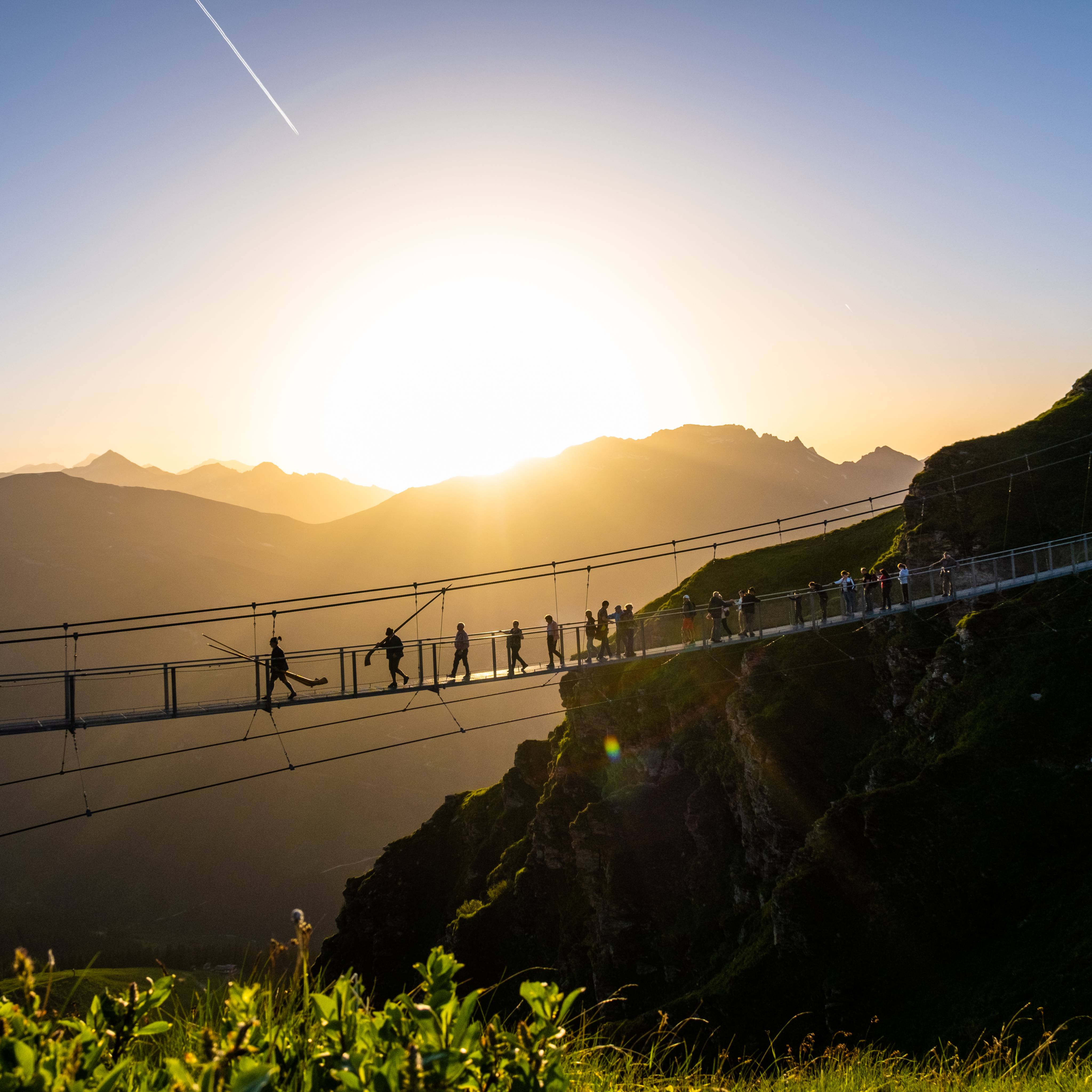 Menschen auf einer riesigen Hängebrücke beim Sonnenuntergang