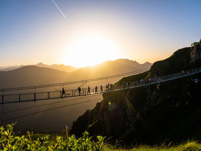 Menschen auf einer riesigen Hängebrücke beim Sonnenuntergang