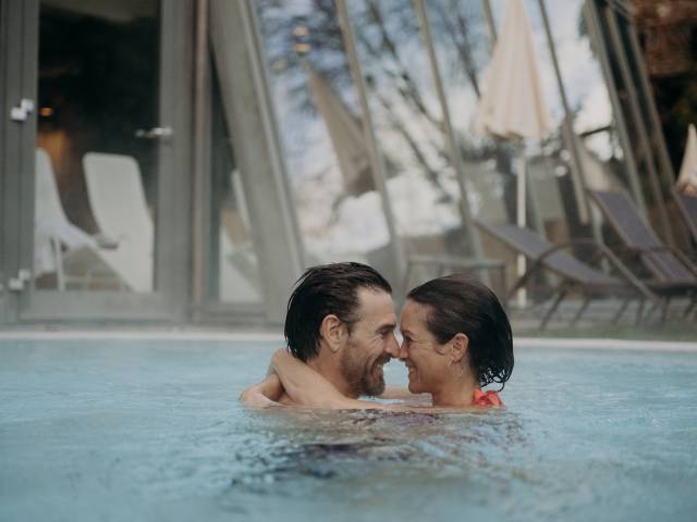 Ein Paar schaut sich verliebt in die Augen und umarmt sich im Hotelpool