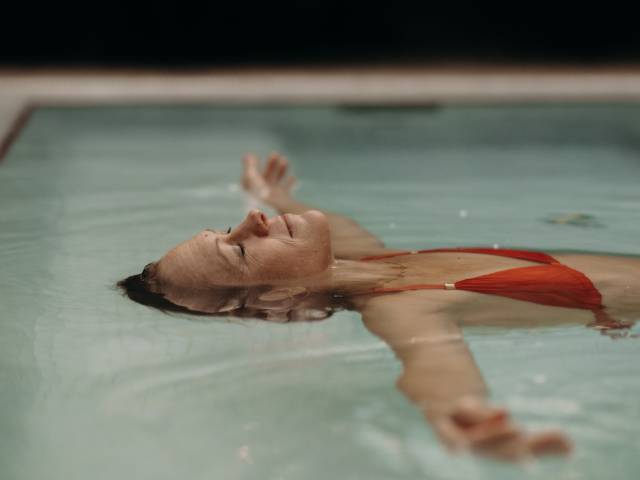 Eine Frau lässt sich im Wasser des Hotelpools treiben