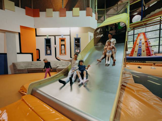 Familie rutsch die riesige Rutsche im Indoorspielplatz