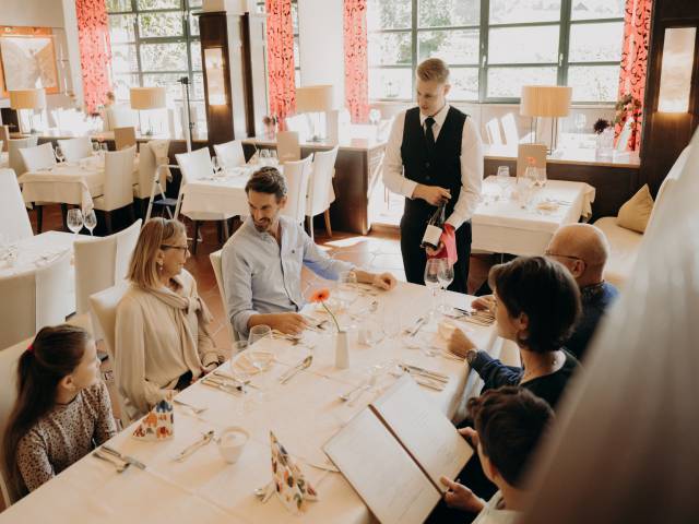 Familie im Restaurant und der Kellner zeigt einen Wein