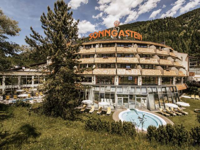 Das Hotel Sonngastein mit Außenpool, Liegewiese und Bergblick im Sommer.
