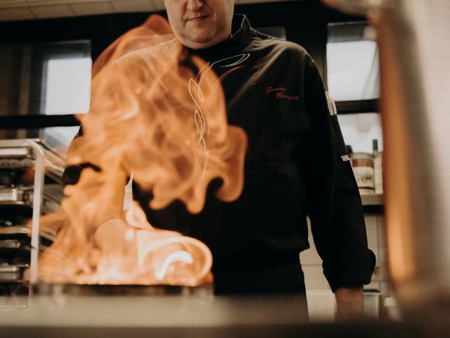 Koch beim Flambieren in Profi-Küche – kreative Kochkunst, Live-Cooking und gehobene Gastronomie
