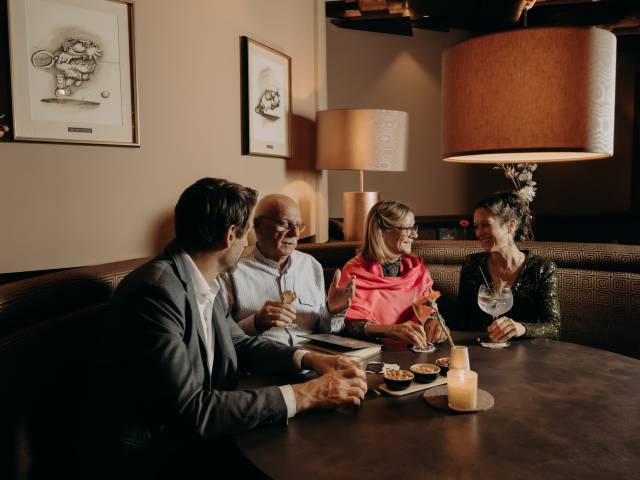 Gäste genießen Cocktails und Gespräche in stilvoller Hotelbar – entspannte Atmosphäre, Genuss und geselliges Beisammensein