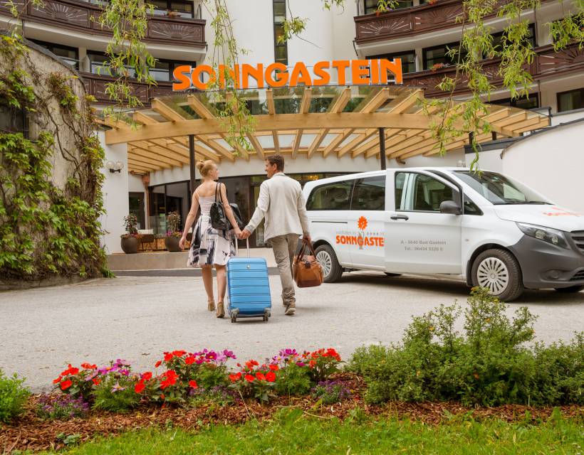 Ein Paar mit Koffer läuft auf den Eingang des Hotel Sonngastein zu