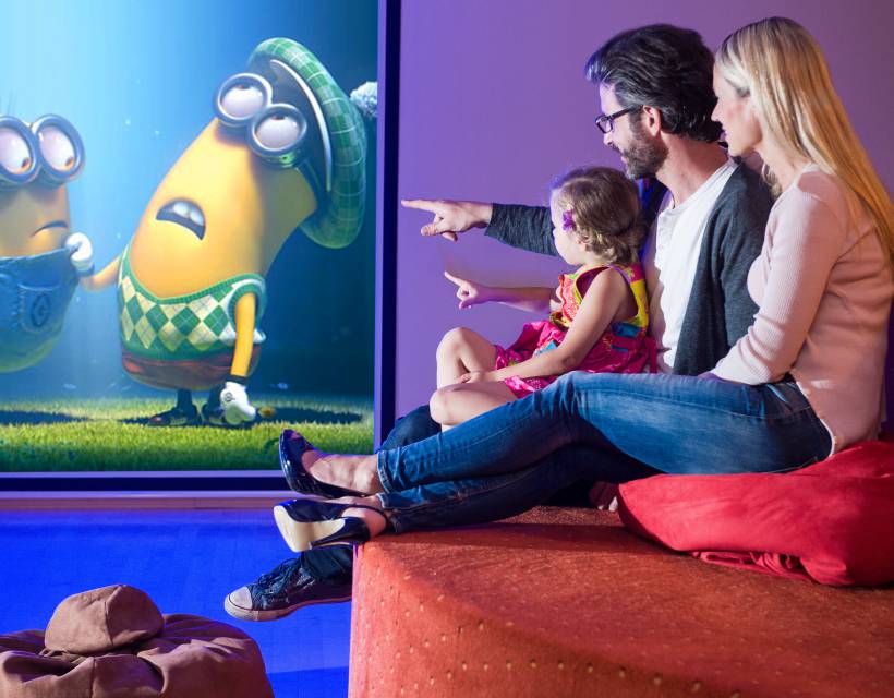 Vater, Mutter und Tochter schauen einen Film im Hotel-Kino