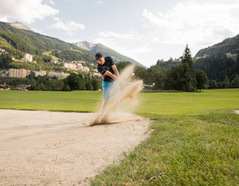 Ein Golfer schlägt einen Ball aus dem Sandbunker