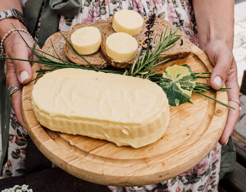 Eine Frau hält ein Jausebrett mit frischen Brot und Butter