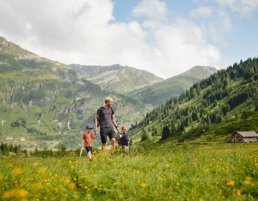 Vater mit Tochter und Sohn läuft über eine Wiese im Gasteinertal