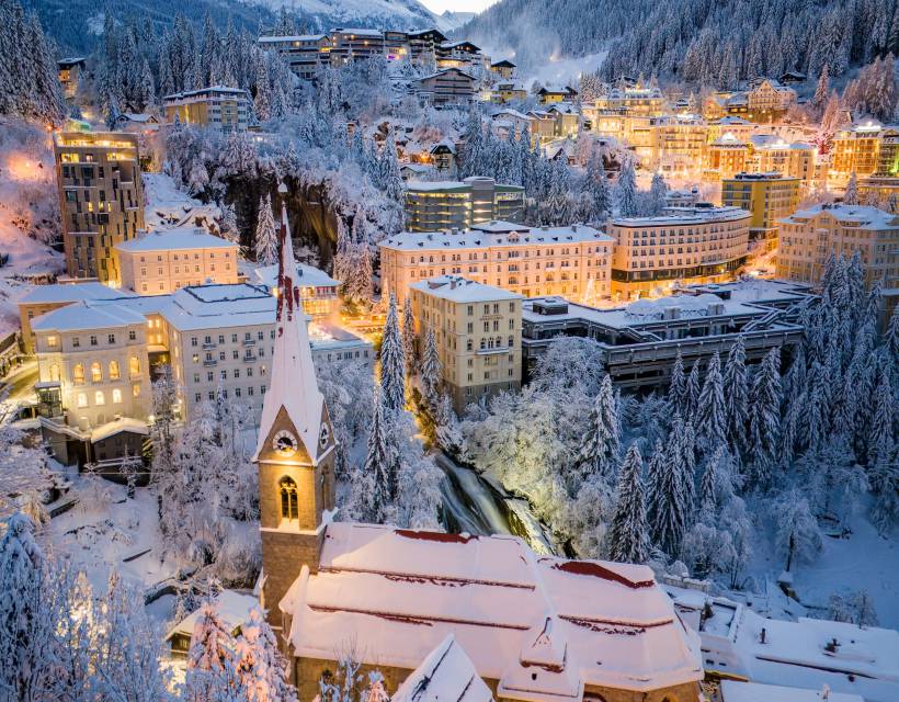 Winterliches Bad Gastein mit verschneiten Bergen, historischer Kirche und beleuchteten Hotels im Gasteinertal.