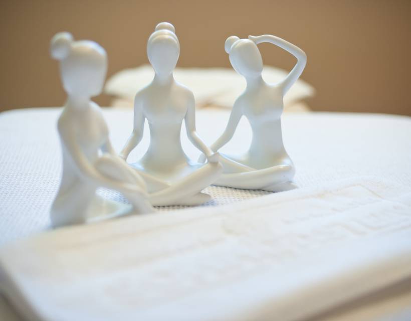 drei kleine weiße Statuen von Frauen die Yoga machen