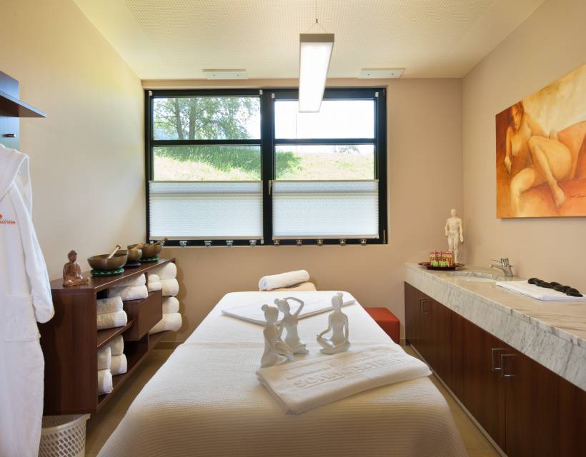 Wellnessbehandlungsraum mit Liege, Handtücher, Bademäntel und Dekorationen