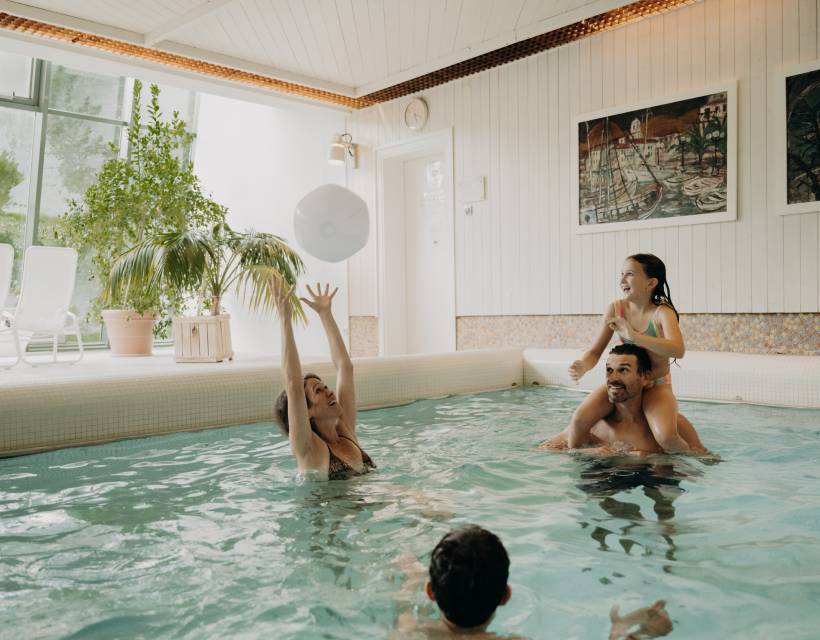 Familie spielt mit einem Wasserball im Hotelpool