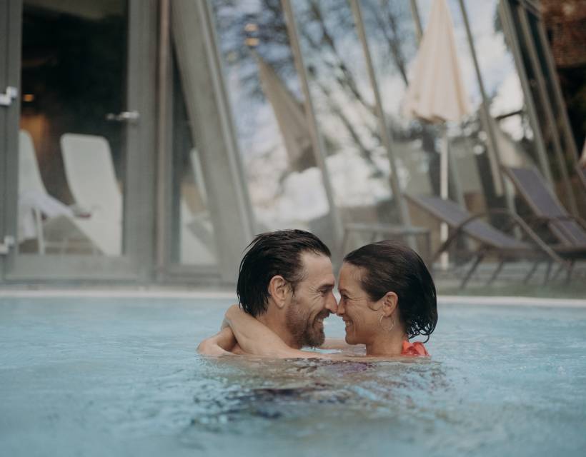 Ein Paar schaut sich verliebt in die Augen und umarmt sich im Hotelpool