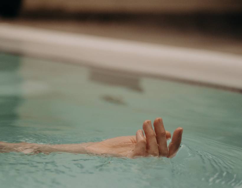Man sieht die Hand einer Frau die sich Wasser treiben lässt