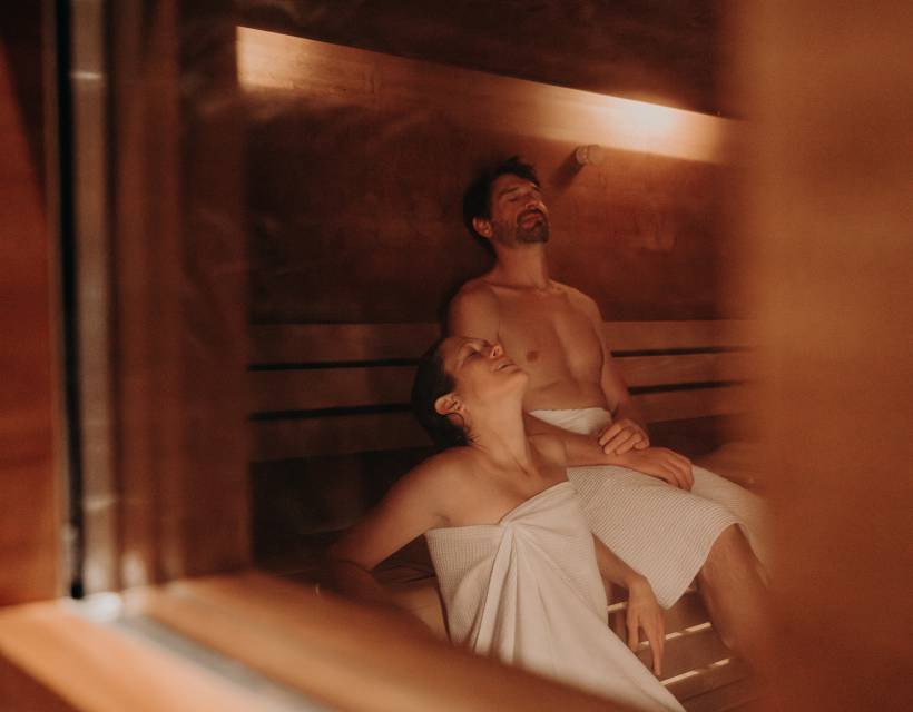 Ein Mann und eine Frau sitzen in der finnischen Sauna und genießen die Wärme
