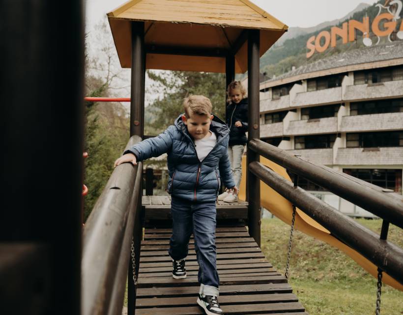 Kinder beim spielen auf dem Spielplatz mit dem Hotel Sonngastein im Hintergrund