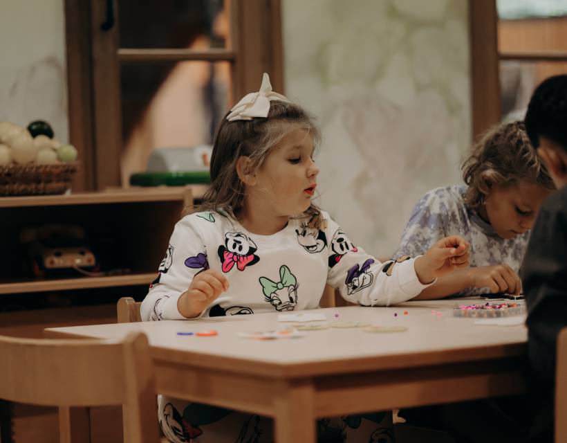 Mädchen machen Halsketten aus Perlen in der Kinderbetreuung im Hotel Sonngastein