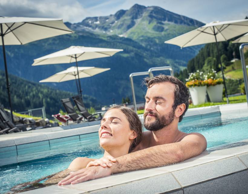 Ein Mann und eine Frau entspannen sich bei schönem Wetter im Aussenpool