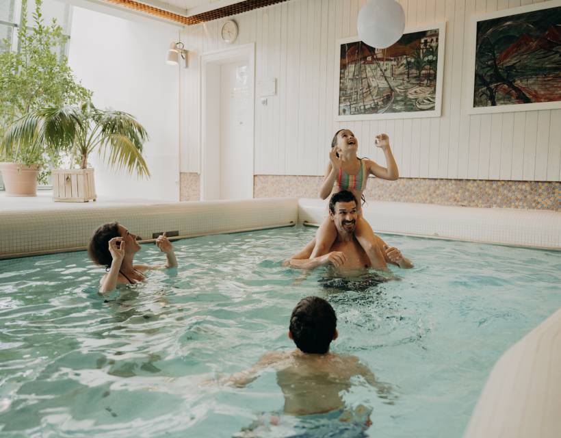 Familie genießt gemeinsamen Badespaß im Indoor-Pool eines Wellnesshotels mit entspannter Atmosphäre