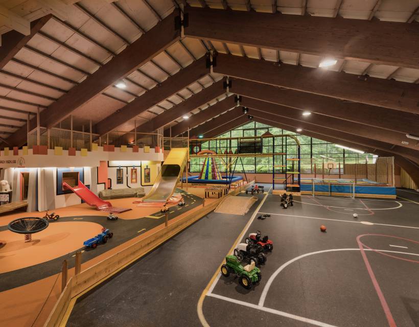 Indoor-Spielplatz mit Rutschen, Klettergerüst und Fahrzeugen im Familienhotel