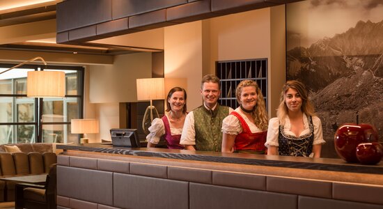 Rezeptions-Team in fescher Tracht in der Hotellobby