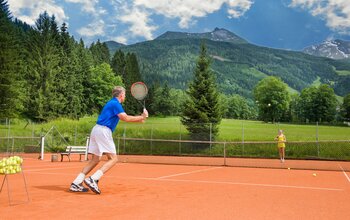 Tennisspieler in Aktion mit Berg-Panorama im Sonngastein