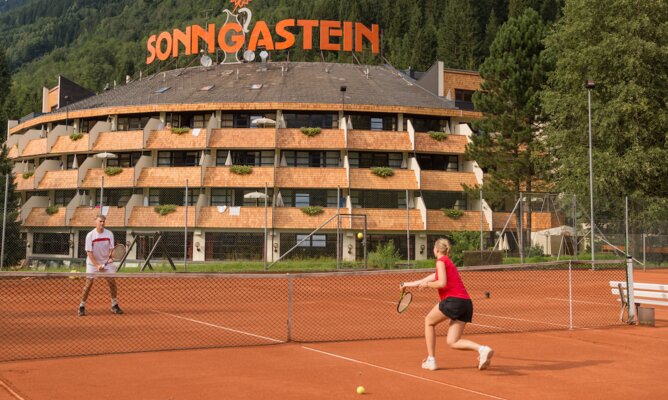 Gastgeber und Gast spielen Tennis am Freiplatz