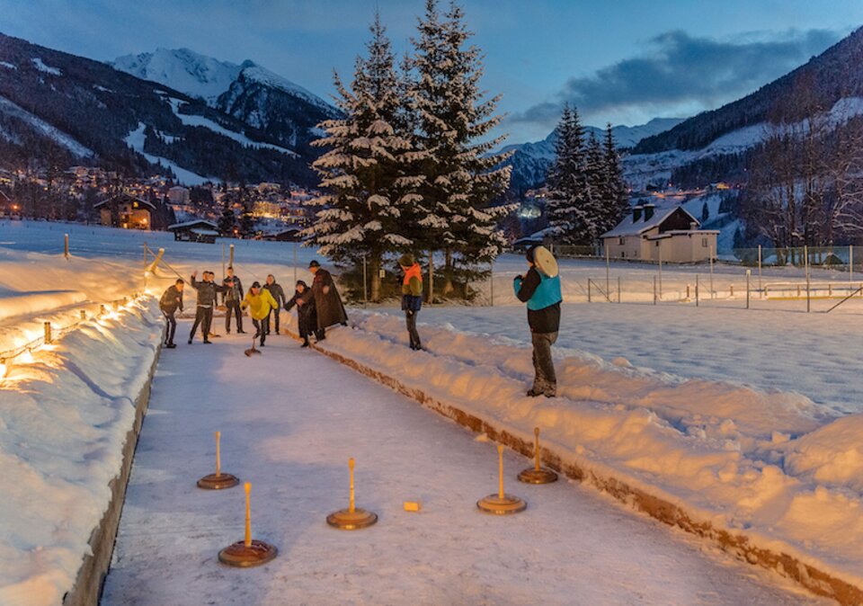 Gäste beim Flutlicht-Eisstockschießen am Abend