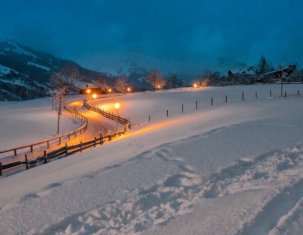 Beleuchteter Spazierweg durch die verschneite Landschaft beim Hotel Sonngastein