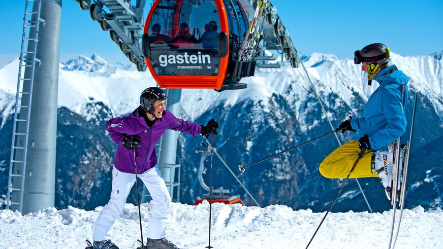 Skifahrer stehen unter der Gondel und genießen das Panorama