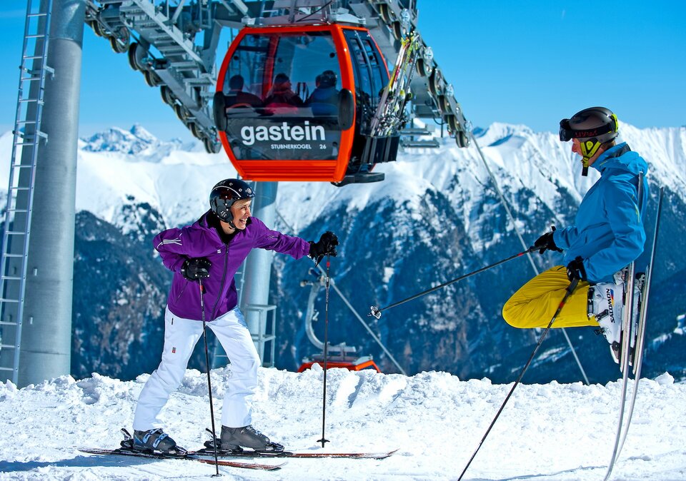 Pärchen steht mit den Ski unter der Gondel