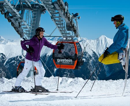 Pärchen steht mit den Ski unter der Gondel