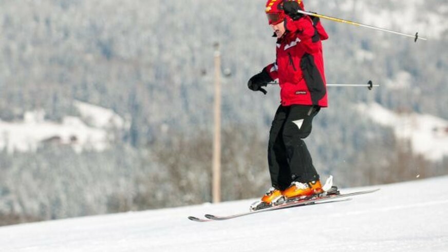 Kind mit rotem Ski-Anorak beim Skifahren